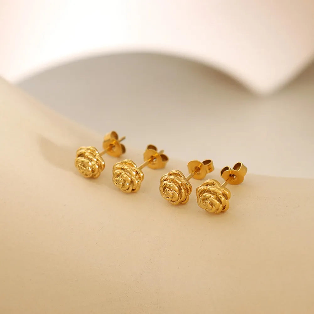 Gold rosebud stud earrings with detailed floral design