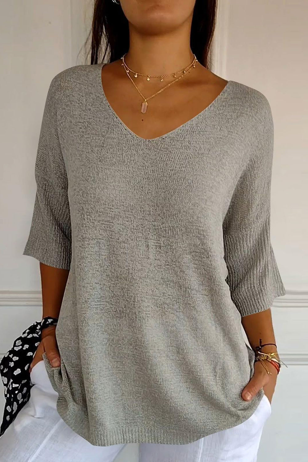 Gray knit sweater with V-neck and flared sleeves, casual style.