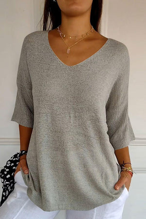 Gray knit sweater with V-neck and flared sleeves, casual style.
