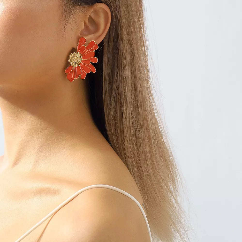 Textured orange flower stud earrings with gold center detail.
