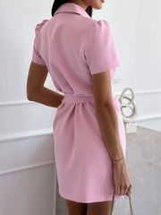 Blush pink tailored blazer dress with short puff sleeves, collar, and matching belt.