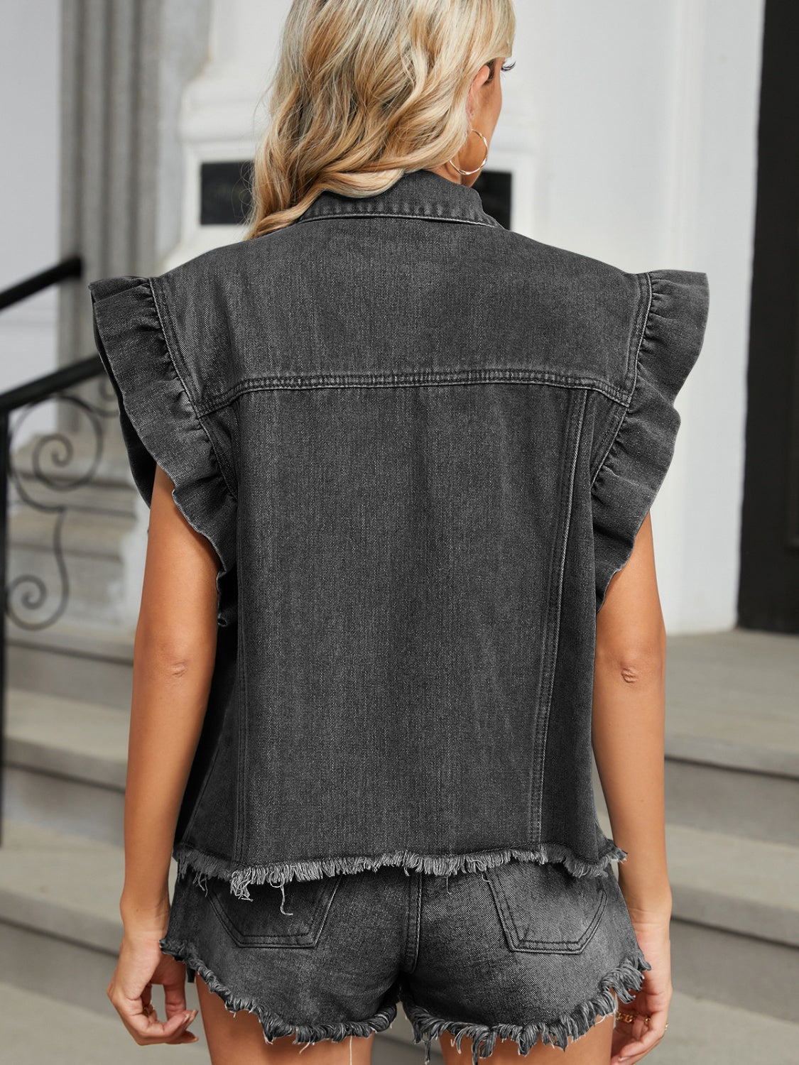 Black denim vest with ruffled cap sleeves and frayed hem.