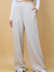 Beige wide-leg lounge pants with pockets and elastic waistband.