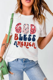 White graphic tee with distressed "God Bless America" text in red, white, and blue patriotic stars and stripes pattern.
