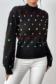 Black blouson sweater with colorful pom-pom embellishments and mock neck.