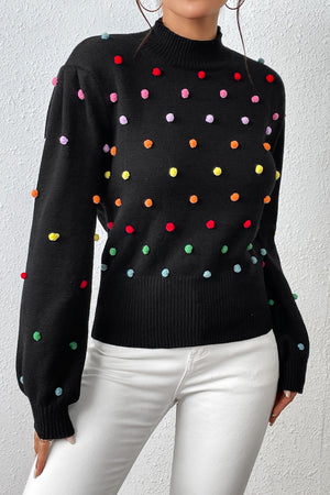 Black blouson sweater with colorful pom-pom embellishments and mock neck.