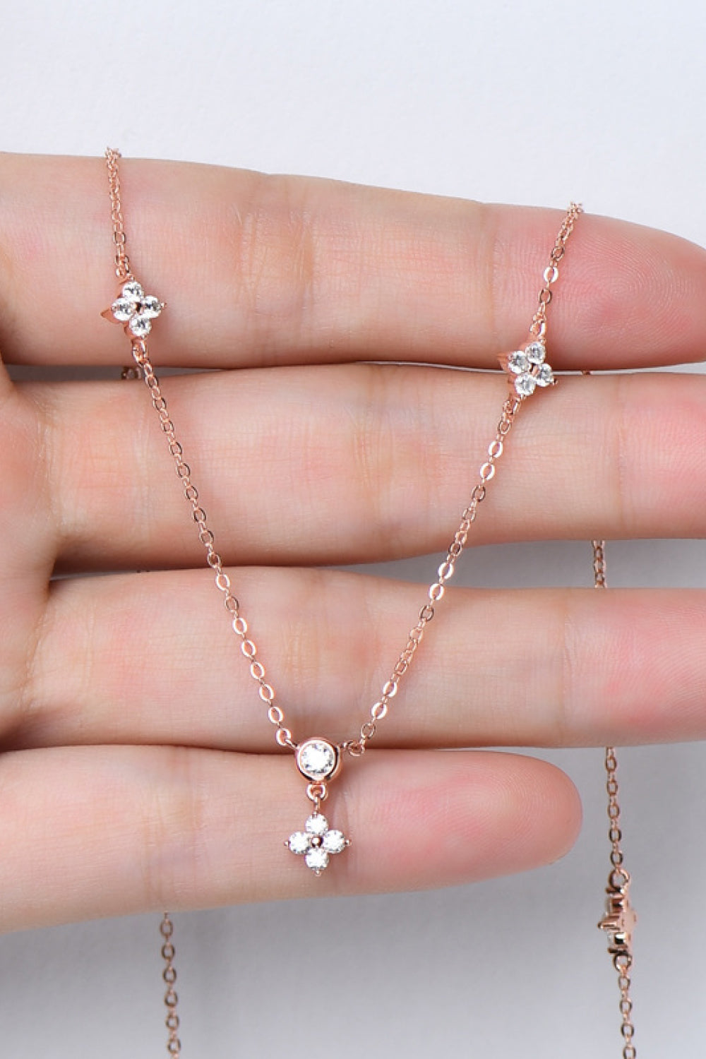 Rose gold necklace with diamond cluster clover charms and a single diamond pendant.