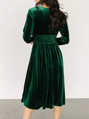 Dark green velvet midi dress with smocked waist and long sleeves.