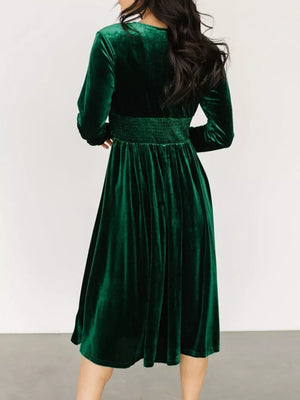 Dark green velvet midi dress with smocked waist and long sleeves.