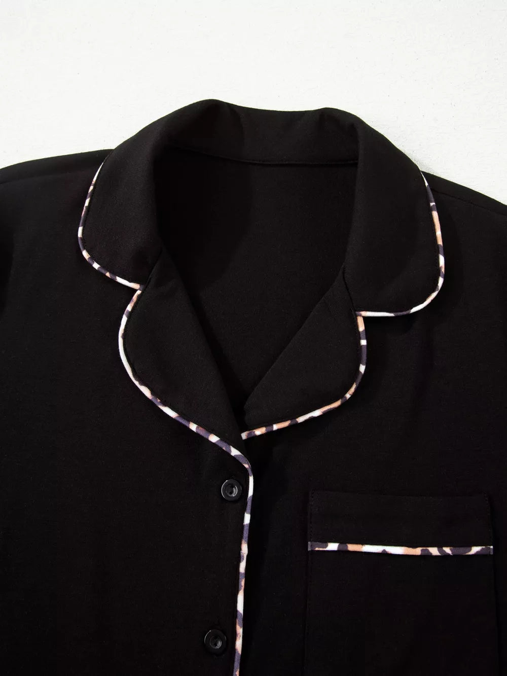 Black pajama set with leopard trim detail on collar, pocket, and buttons.