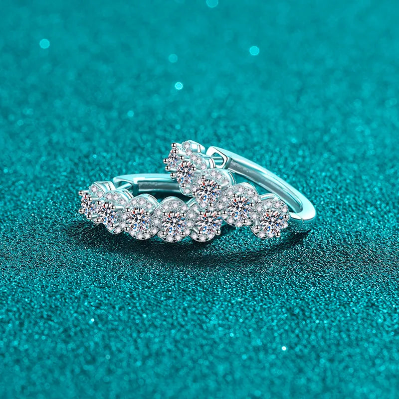 Silver moissanite cluster huggie hoop earrings with sparkling round-cut stones.
