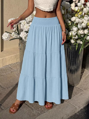 Blue smocked tiered maxi skirt with flowing fabric and textured detail.