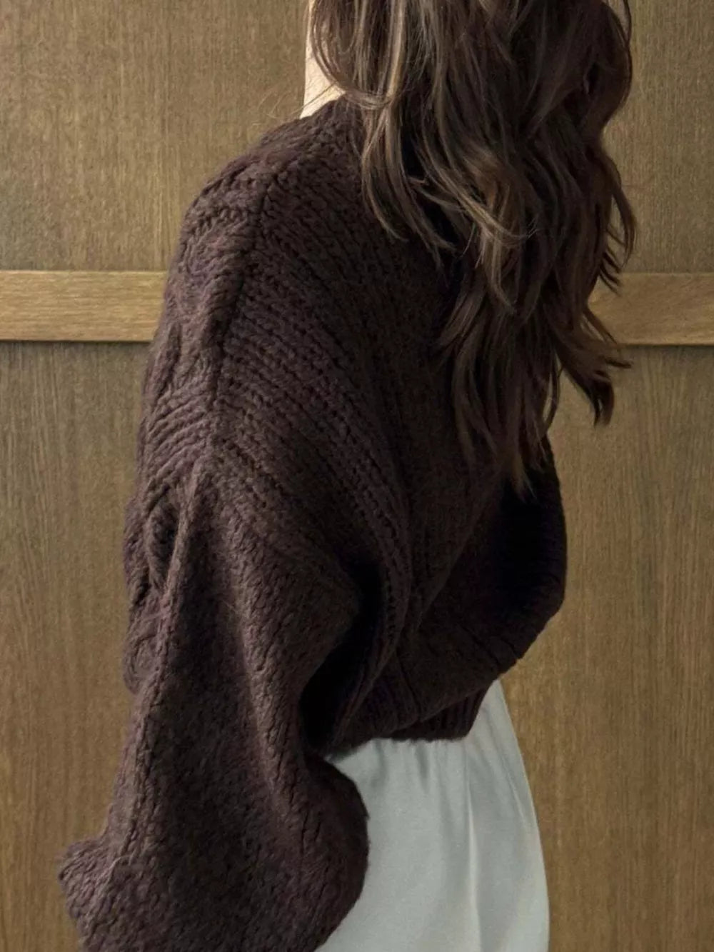 Brown cable-knit cardigan with textured sleeves and a relaxed fit.
