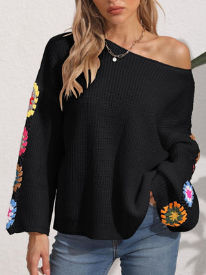 Black knit sweater with colorful granny square crochet sleeves, off-the-shoulder neckline.