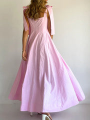Pink maxi dress with bow tie shoulder straps and square neckline.