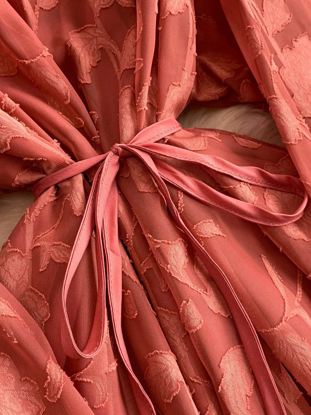 Embroidered tie-waist dress in rust with a textured leaf pattern and a satin sash.