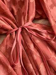 Embroidered tie-waist dress in rust with a textured leaf pattern and a satin sash.