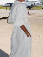 White midi dress with lapel collar, tie waist, and cuffed sleeves.