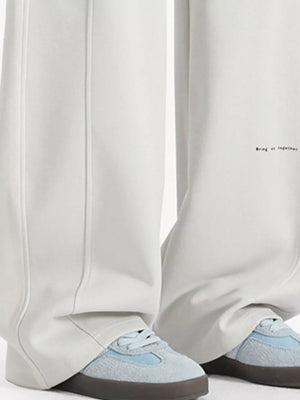 Ivory wide-leg sweatpants with drawstring detail and subtle text graphic.