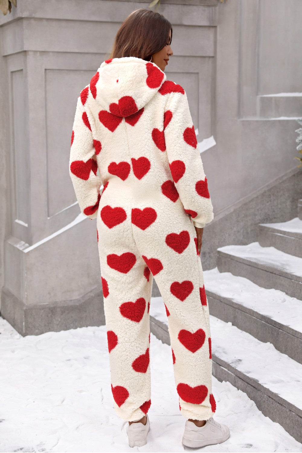 Cream sherpa onesie with red heart print and hood.