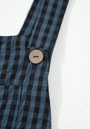 Dark blue gingham overalls with a wooden button detail on the strap.