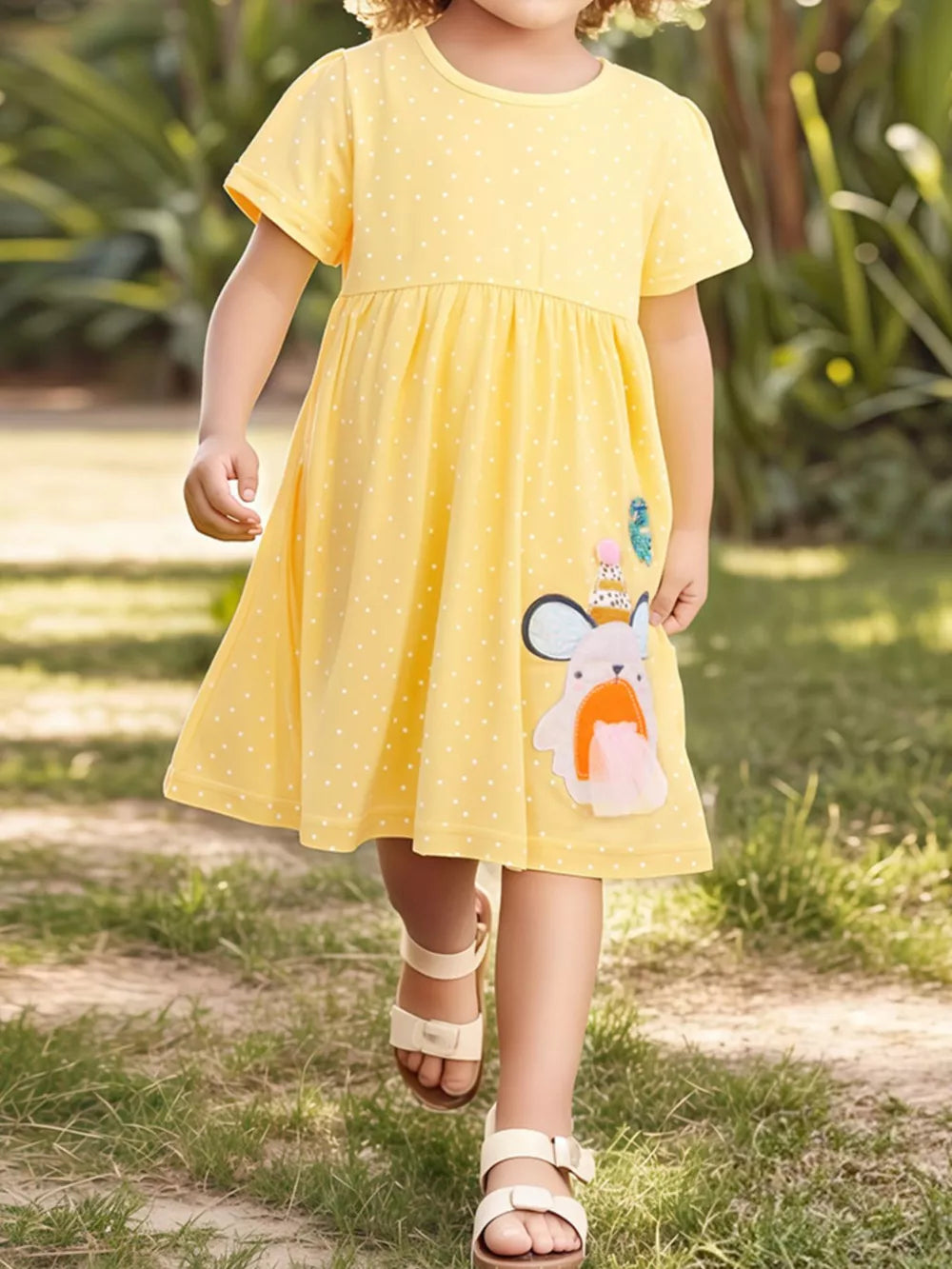 Yellow polka dot toddler dress with cartoon applique and short sleeves.