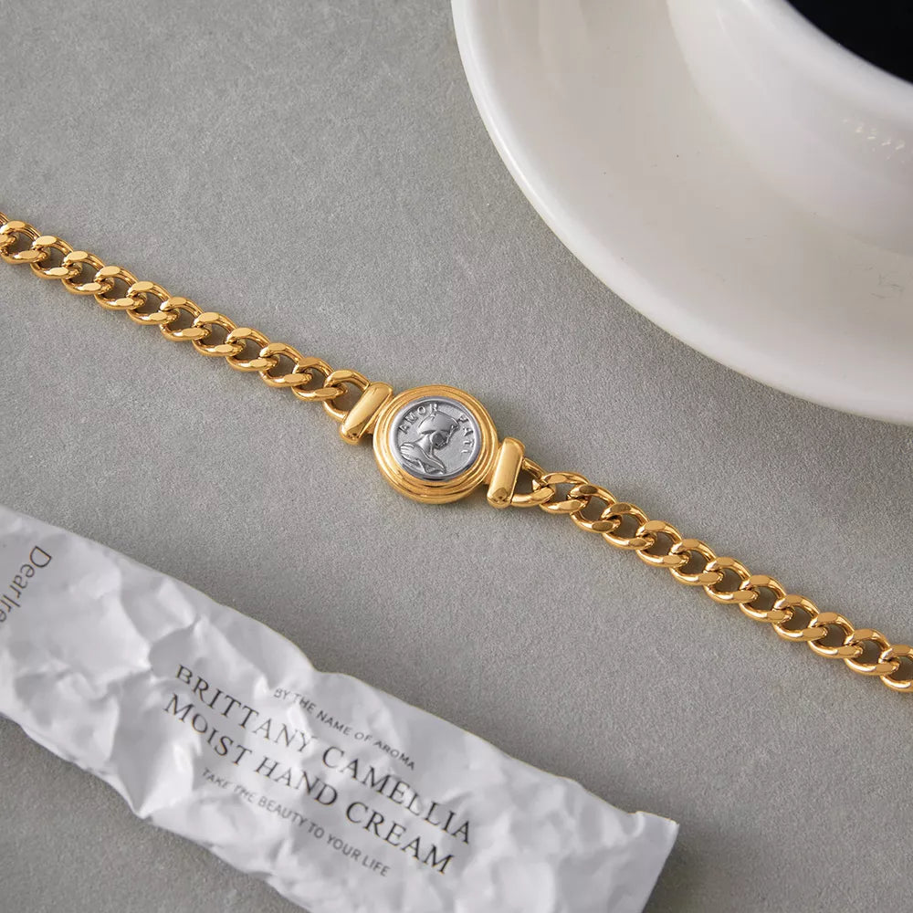 Gold curb chain necklace with a vintage coin charm and Roman profile detail.