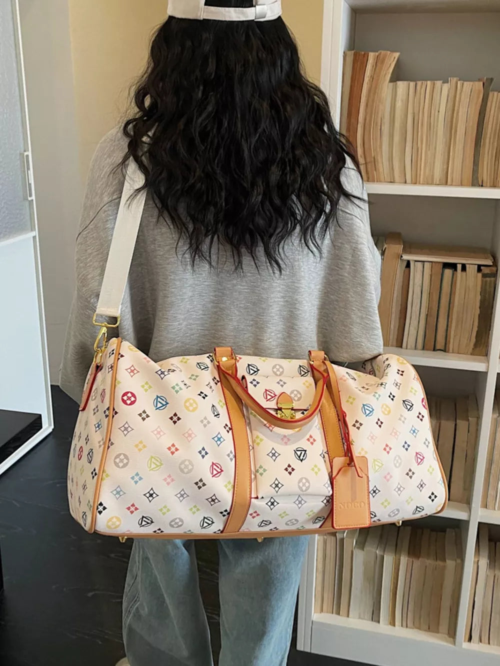 Vibrant monogram leather travel bag with adjustable strap and tan trim.