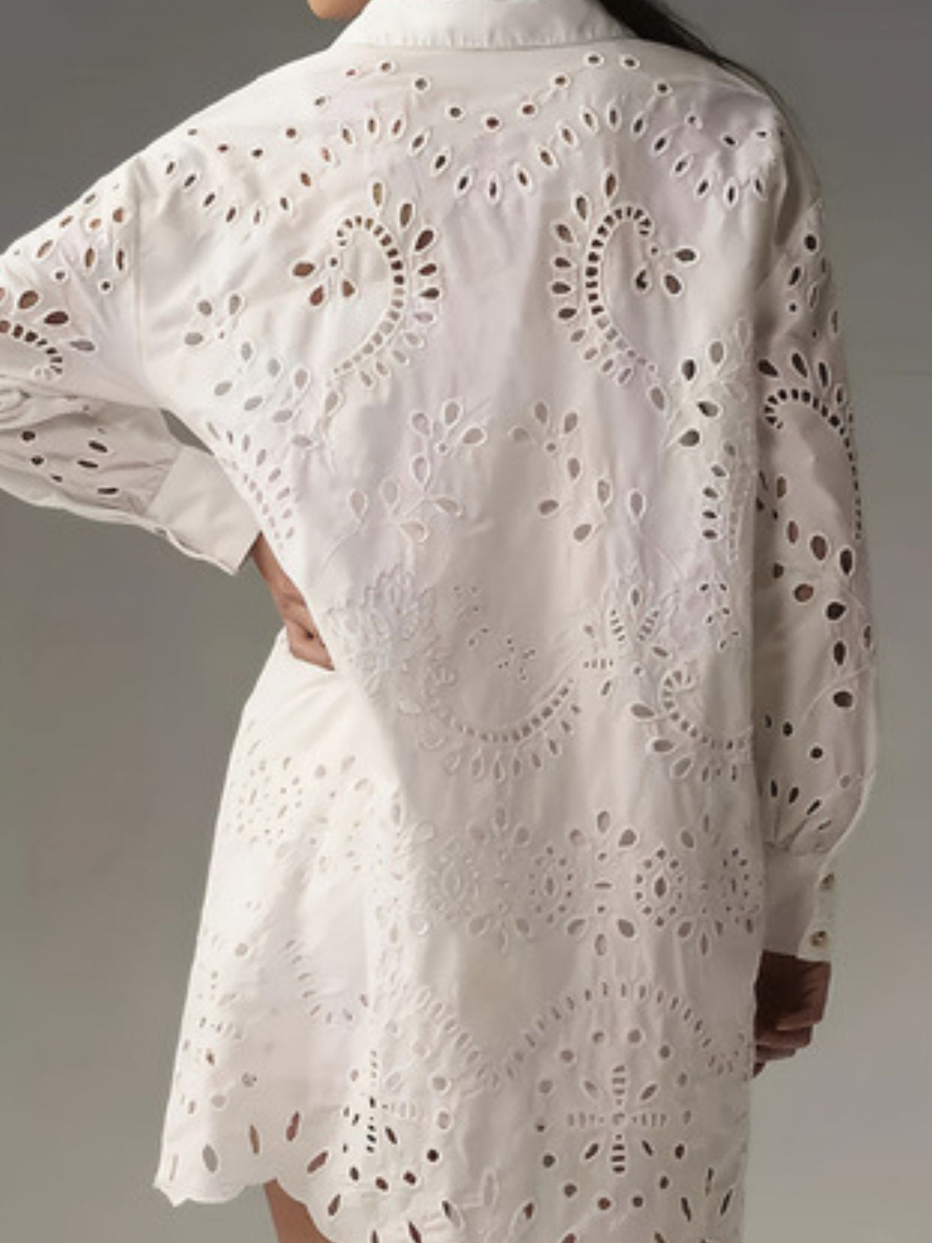 White eyelet longline button-up shirt with intricate cutout details and scalloped hem.