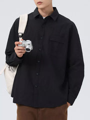 Black textured oversized button-up shirt with a chest pocket and classic collar.