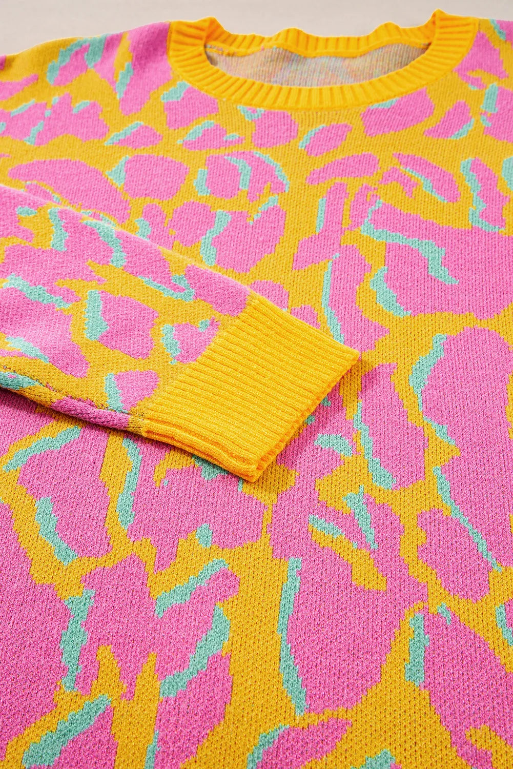 Women's crew knit sweater in fuchsia pink abstract leopard print with yellow trim.