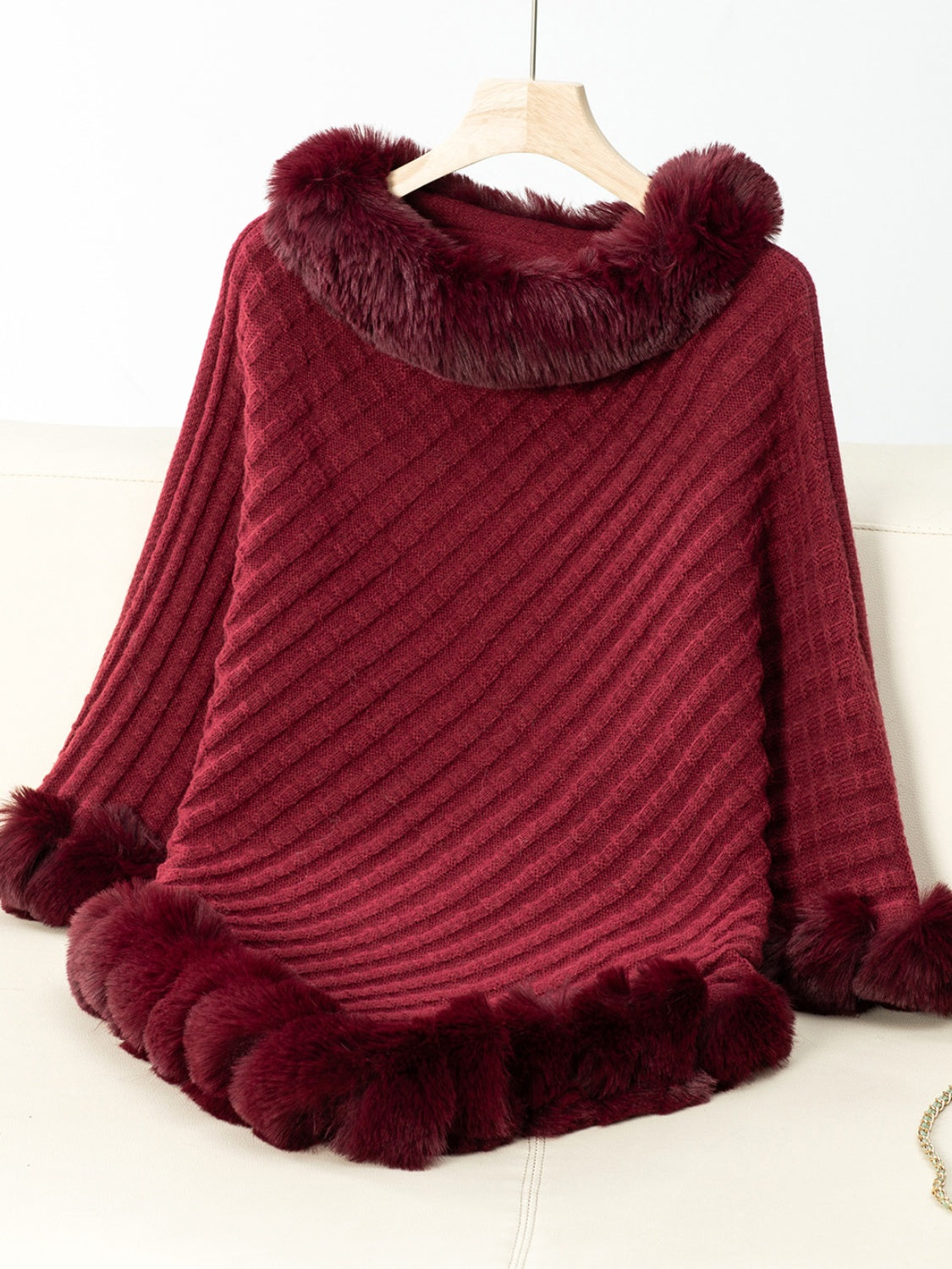 Burgundy knit poncho with faux fur trim at the neckline and hem.