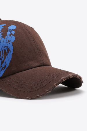Chestnut baseball cap with distressed brim and blue graffiti art detail.