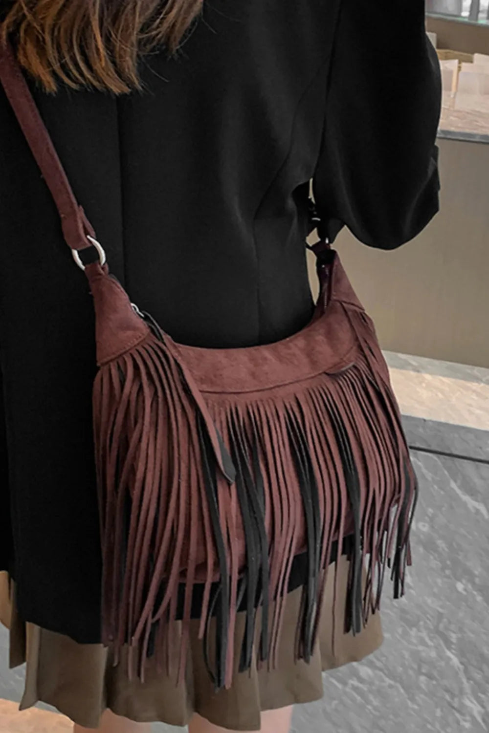 Bohemian suede crescent crossbody bag with fringe detail in dark brown.