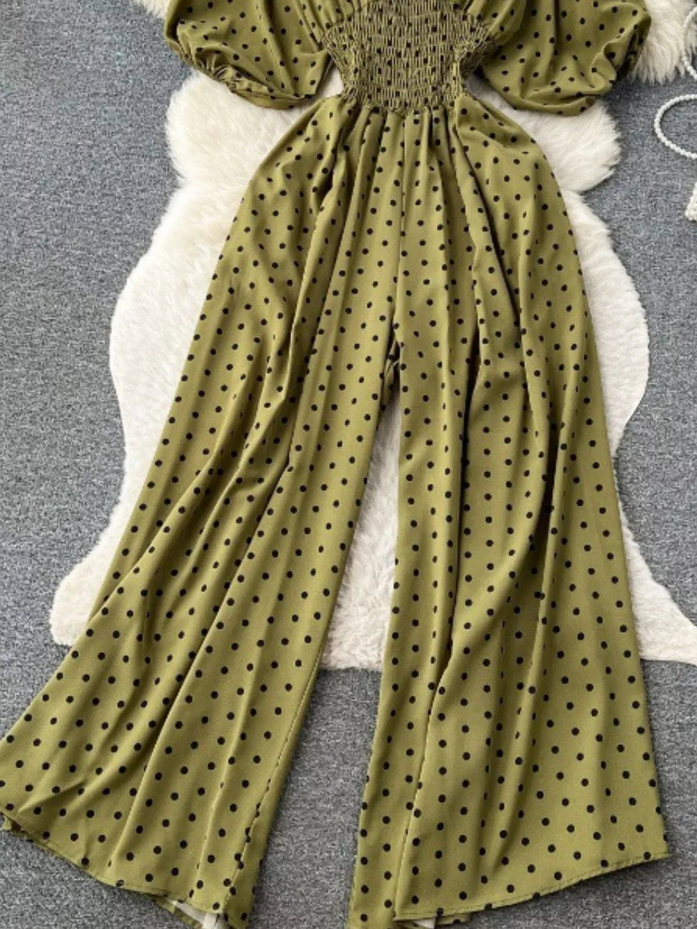 Army green polka dot smocked wide-leg romper with puff sleeves.