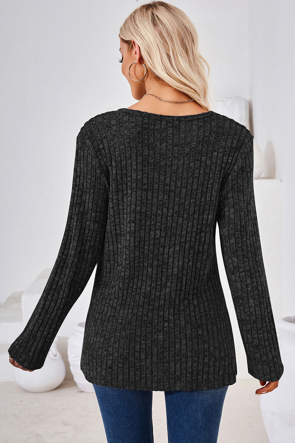 Black ribbed knit sweater with long sleeves and a crew neck.