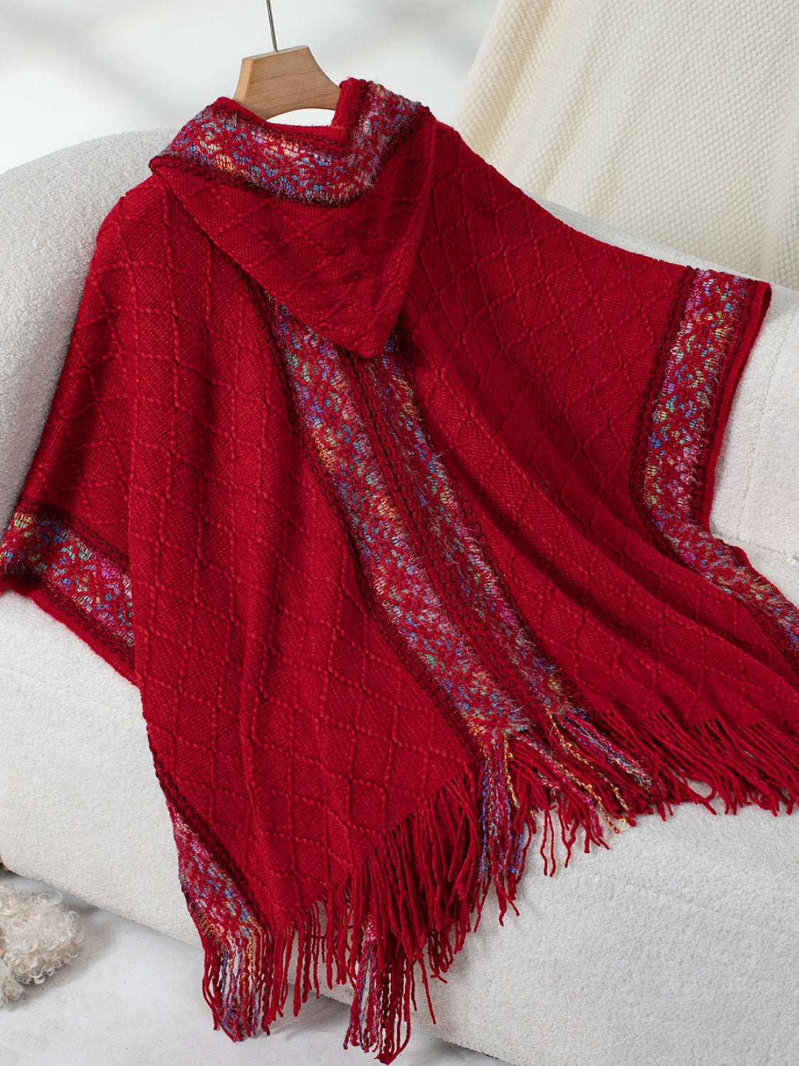 Red knit hooded wrap with diamond pattern and colorful embroidered trim.