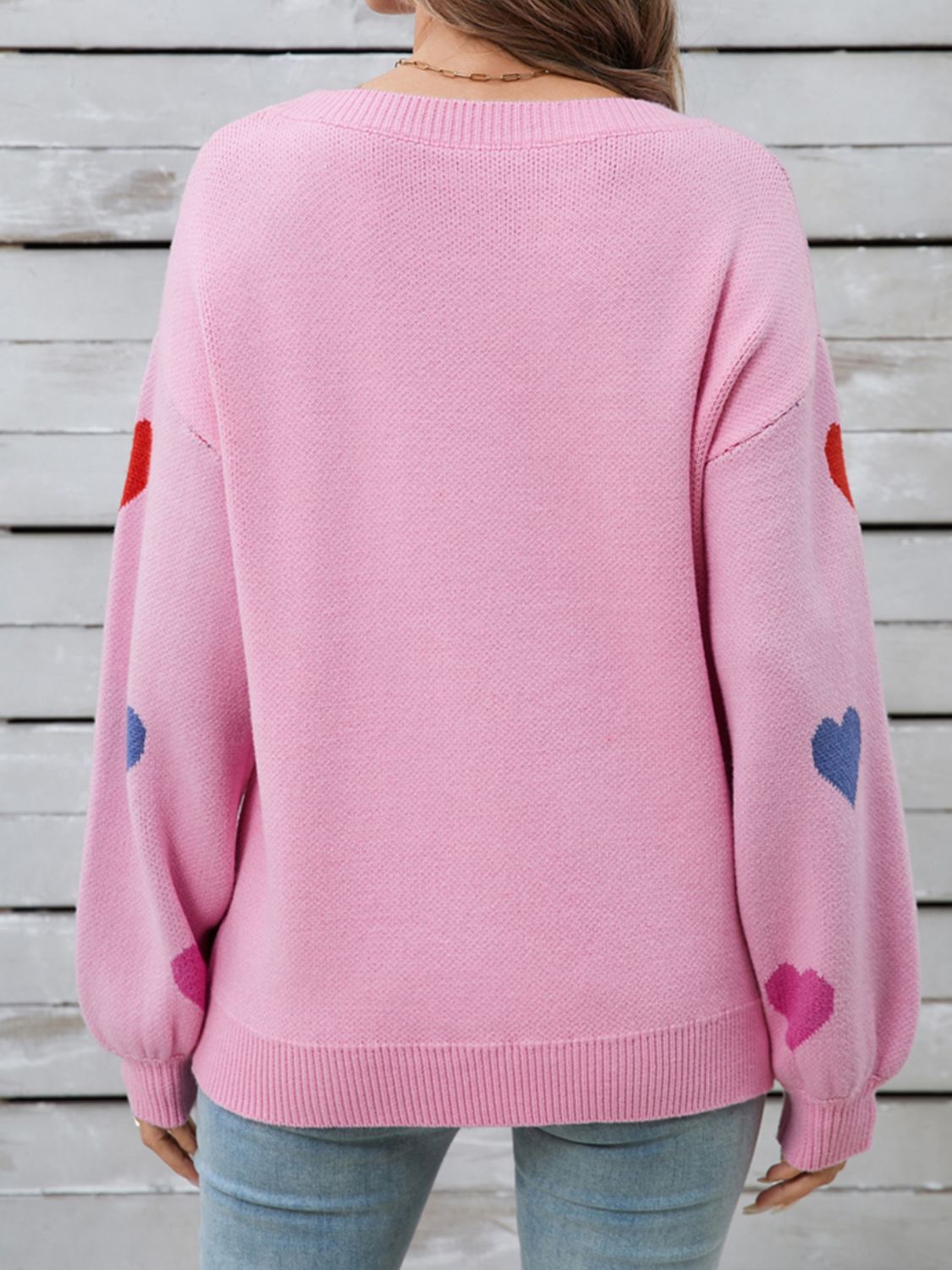 Pink acrylic knit sweater with bubble sleeves and scattered heart motifs.