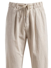Beige linen drawstring trousers with pleats and elastic waistband.