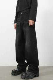 Faded black baggy denim trousers with a relaxed fit, styled with chunky boots.