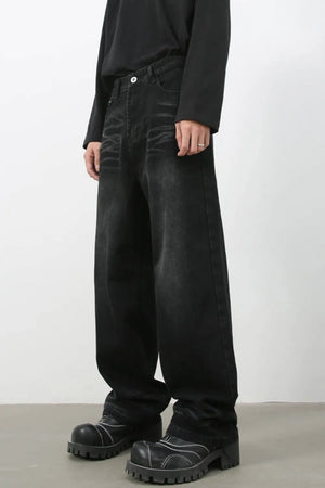 Faded black baggy denim trousers with a relaxed fit, styled with chunky boots.