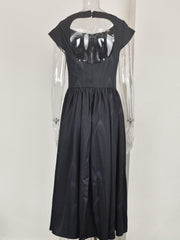 Black cap sleeve midi dress with a-line skirt and open back detail.