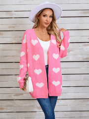 Pink acrylic cardigan with white heart intarsia pattern, open front, long sleeves.
