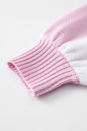 Dusty pink and white acrylic knit sweater sleeve detail with ribbed cuff.