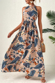 Halter neck maxi dress with floral print and tie waist, in tan with blue and orange flowers.
