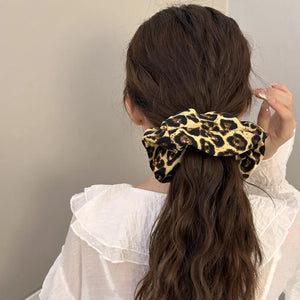 Leopard print silk scrunchie in tan and black, holding back a ponytail.
