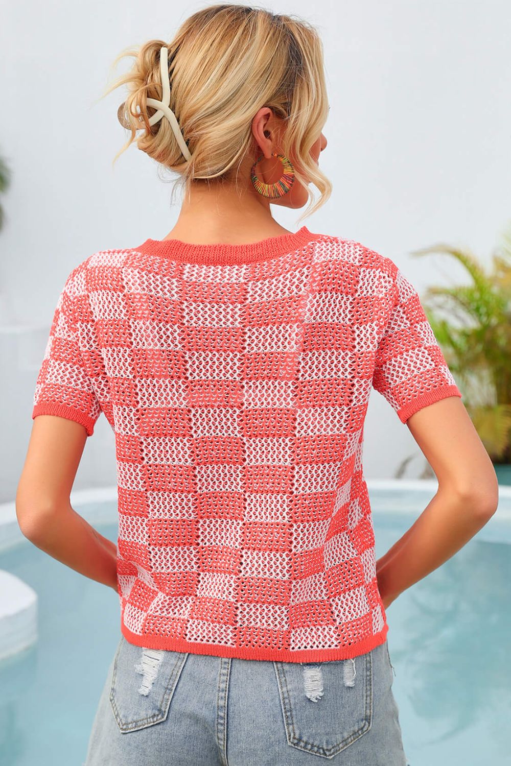 Checkerboard knit crewneck top in orange and white with short sleeves.