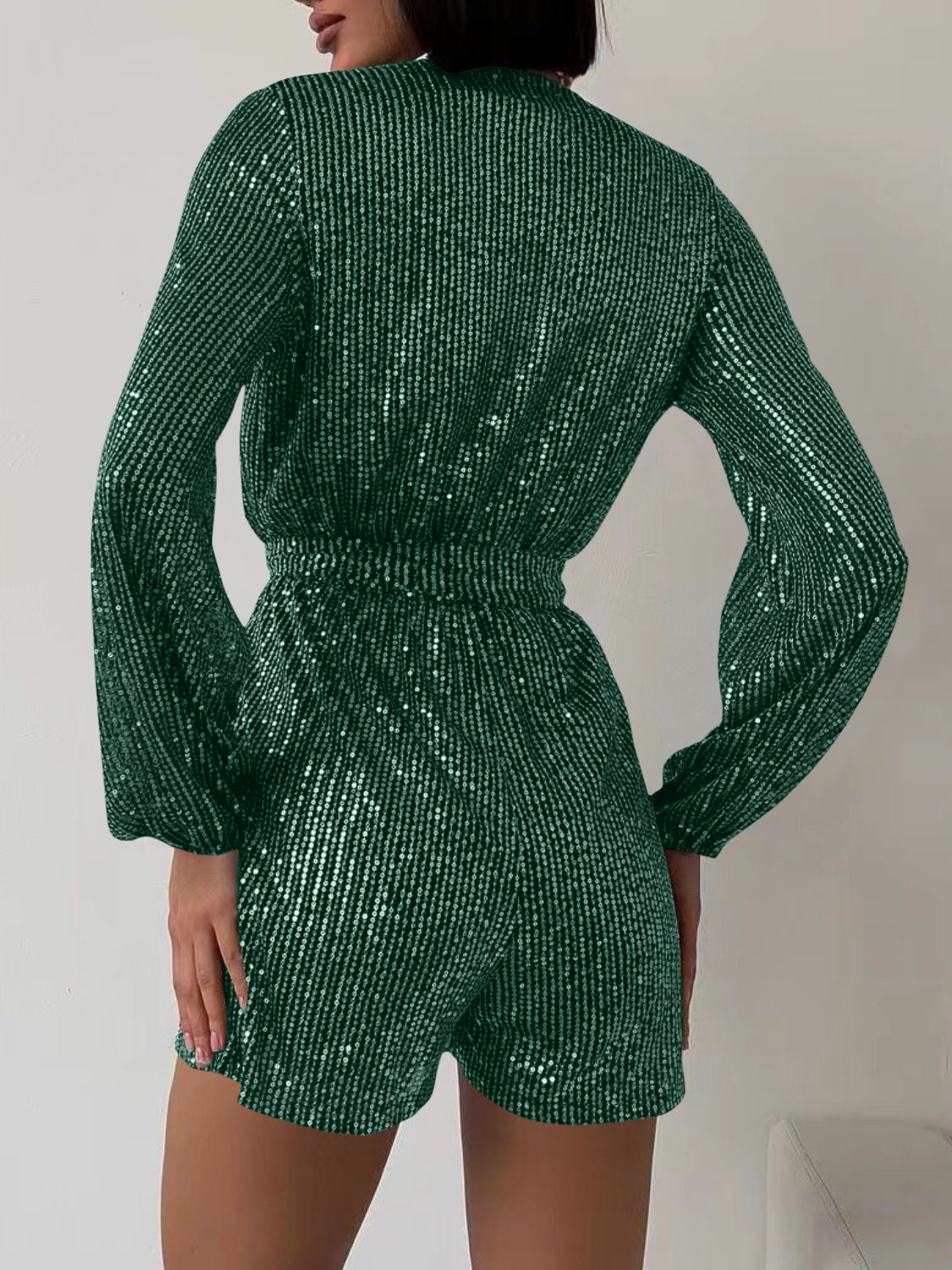 Dark green sequin wrap romper with blouson sleeves and cinched waist.