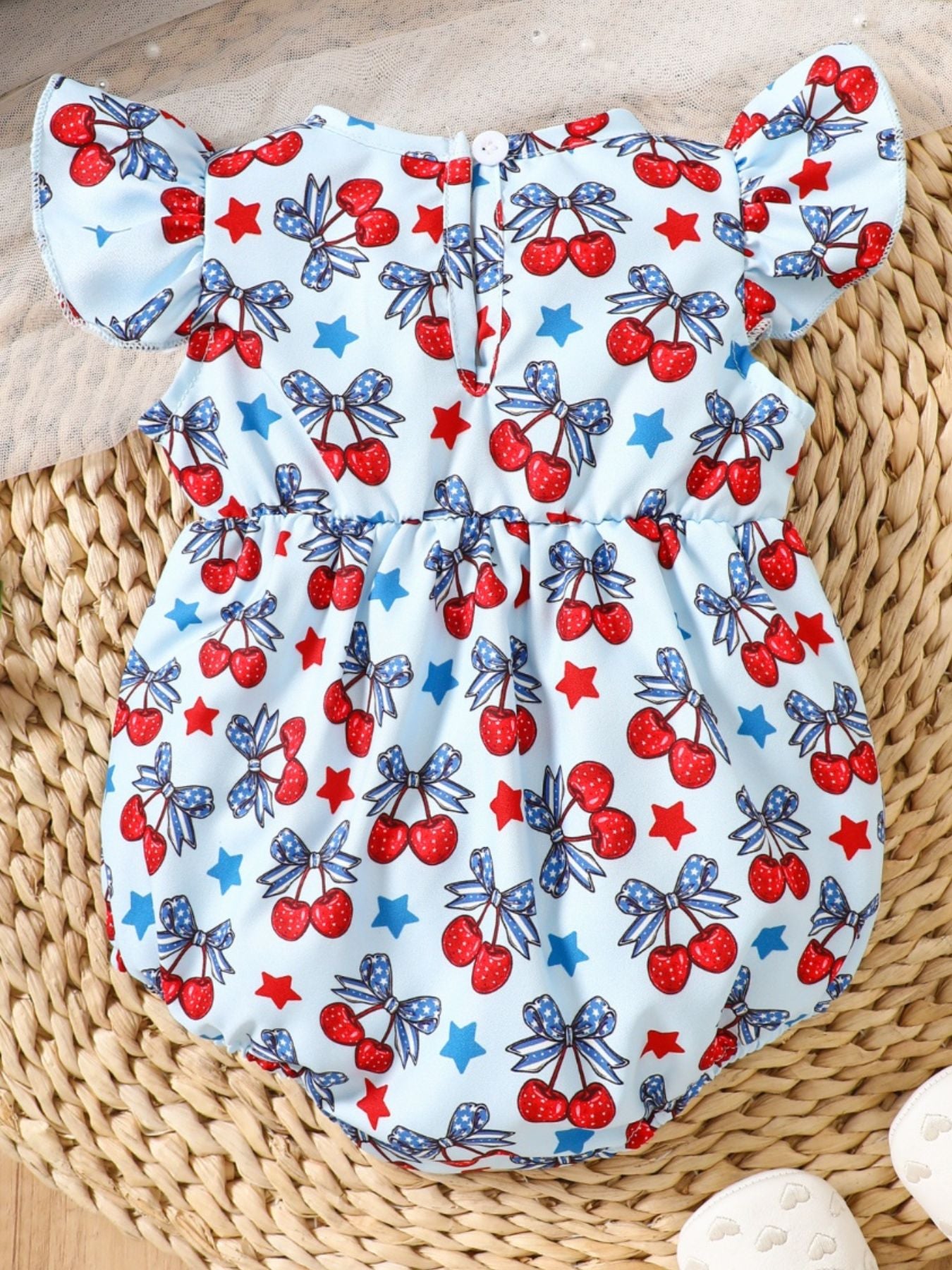 Baby one-piece with cherry and star print, ruffle sleeves, and a light blue cotton fabric.