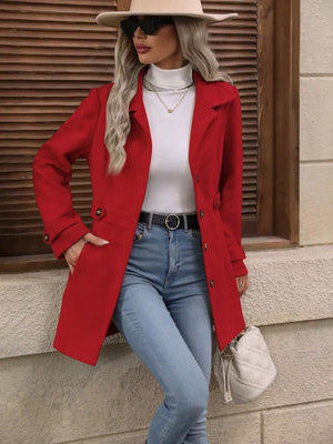 Scarlet button-up trench coat with cinched waist and button details, worn open over a white turtleneck.
